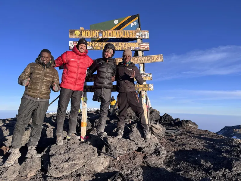 Climbers and their guides at the Uhuru Peak summit sign on a Kilimanjaro climbing tour by the Rongai Route, Tanzania