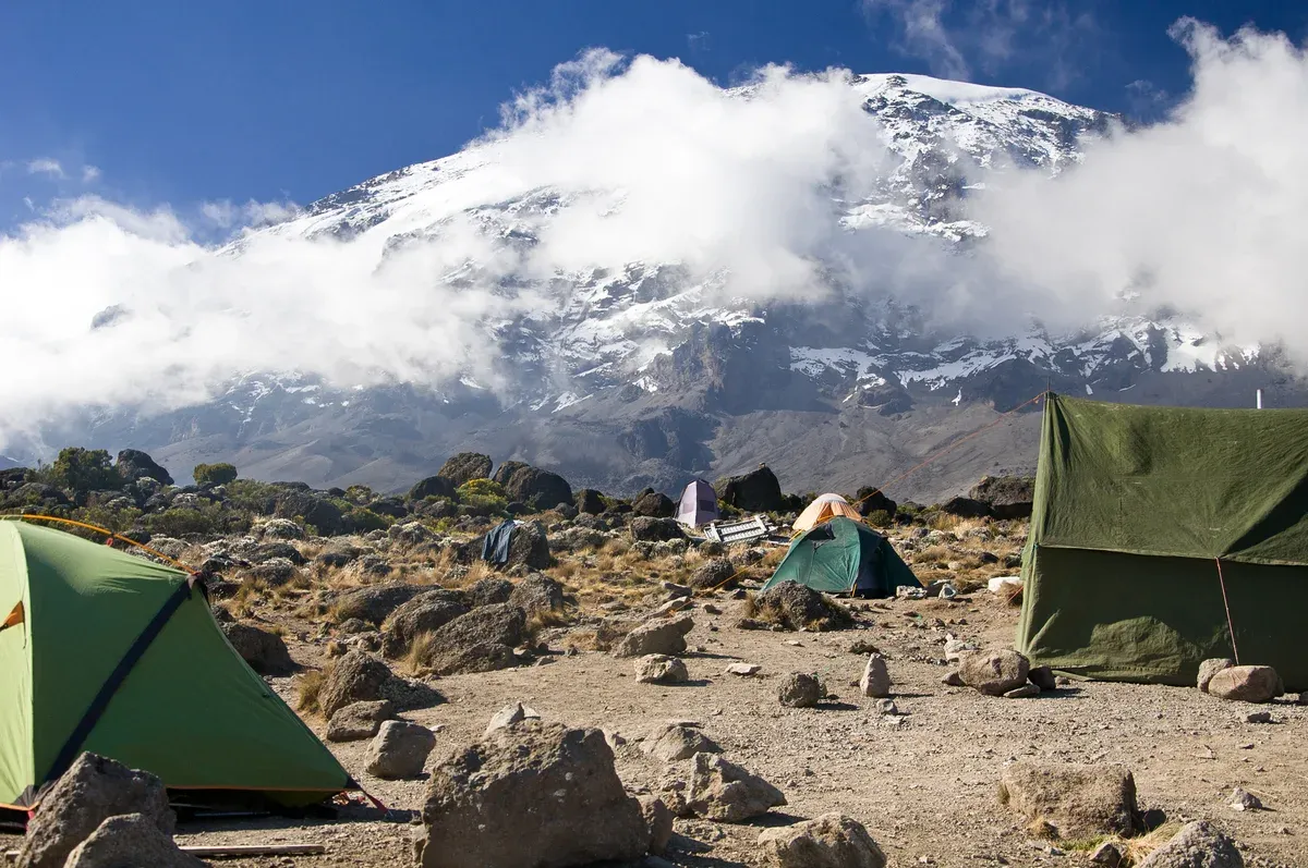Tents at Karanga Camp under the cloud-wrapped summit, a sight on Kilimanjaro climbing tours